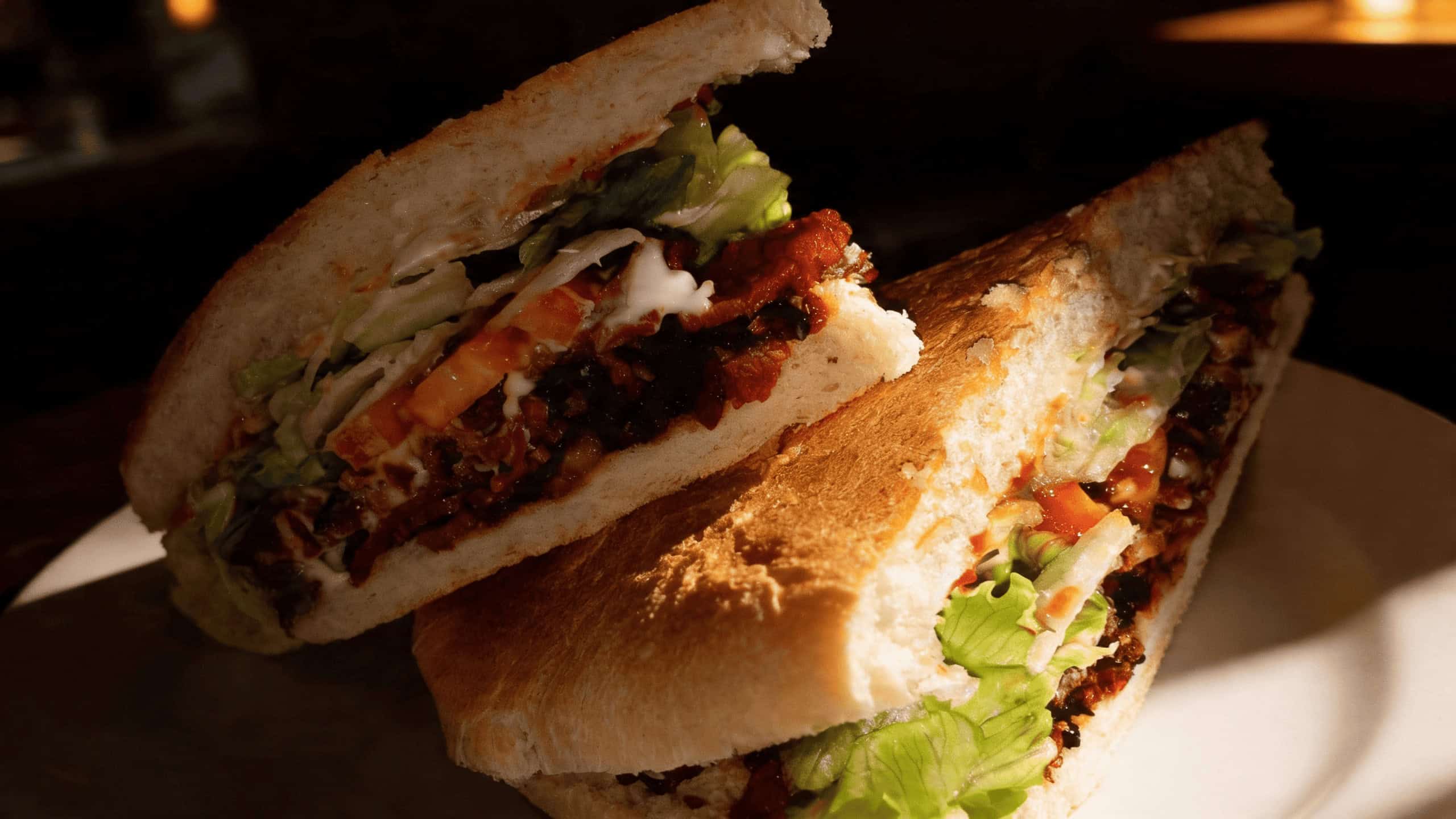 Loaded Puerto Rican sandwich stacked with meats, lettuce, and onions, served with a bottle of Malta India at El Sandwich-on TX in Killeen, TX